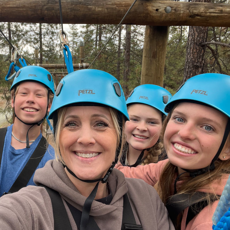 Students in helmets smiling together on a high ropes course