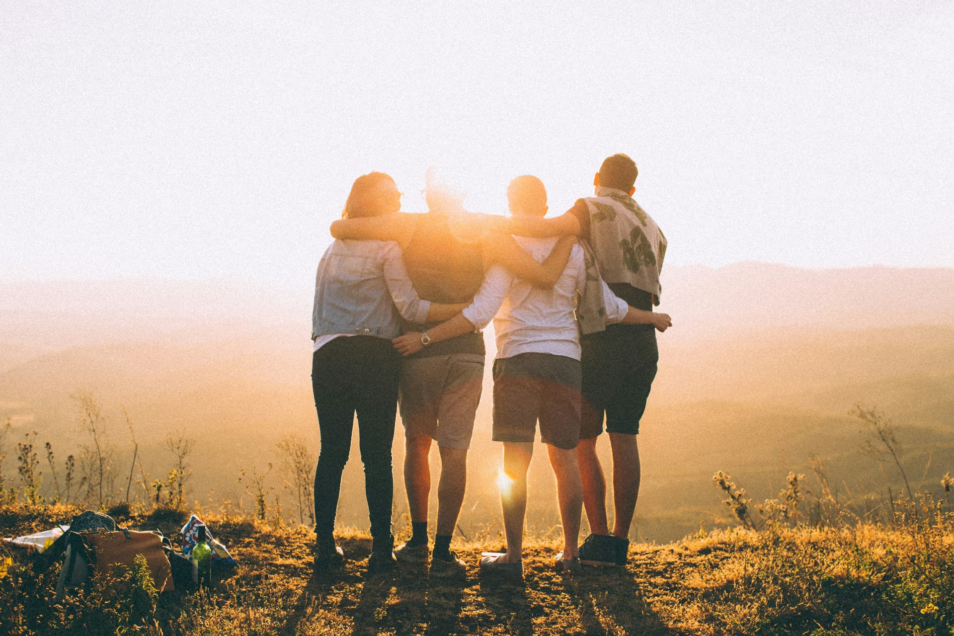 Friends standing arm in arm overlooking the hills at sunset