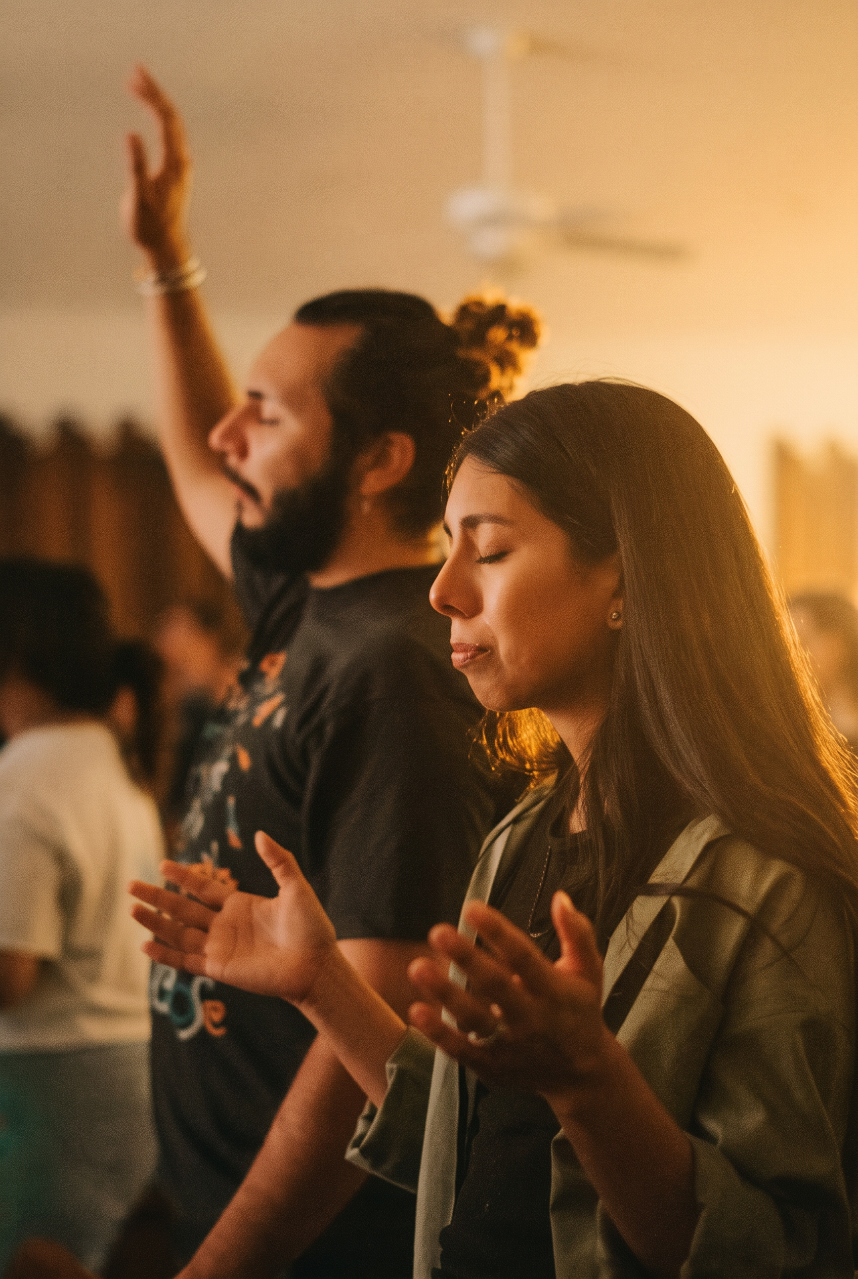 A woman and man worshipping with eyes closed and hands raised